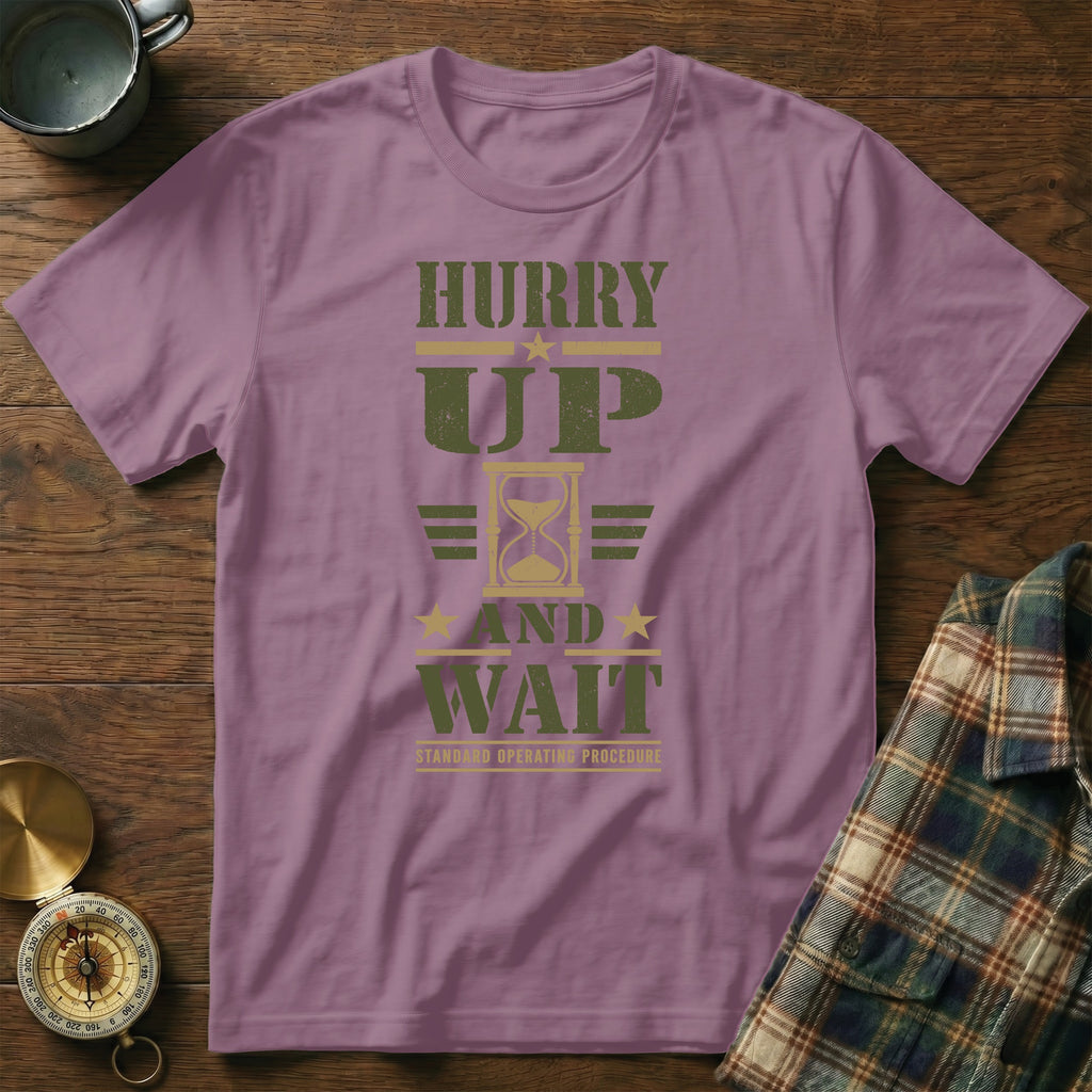 Mauve short-sleeve t-shirt with green text reading HURRY UP AND WAIT and an hourglass graphic.