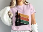 Pink t-shirt with abstract forest and mountain sunset graphic.