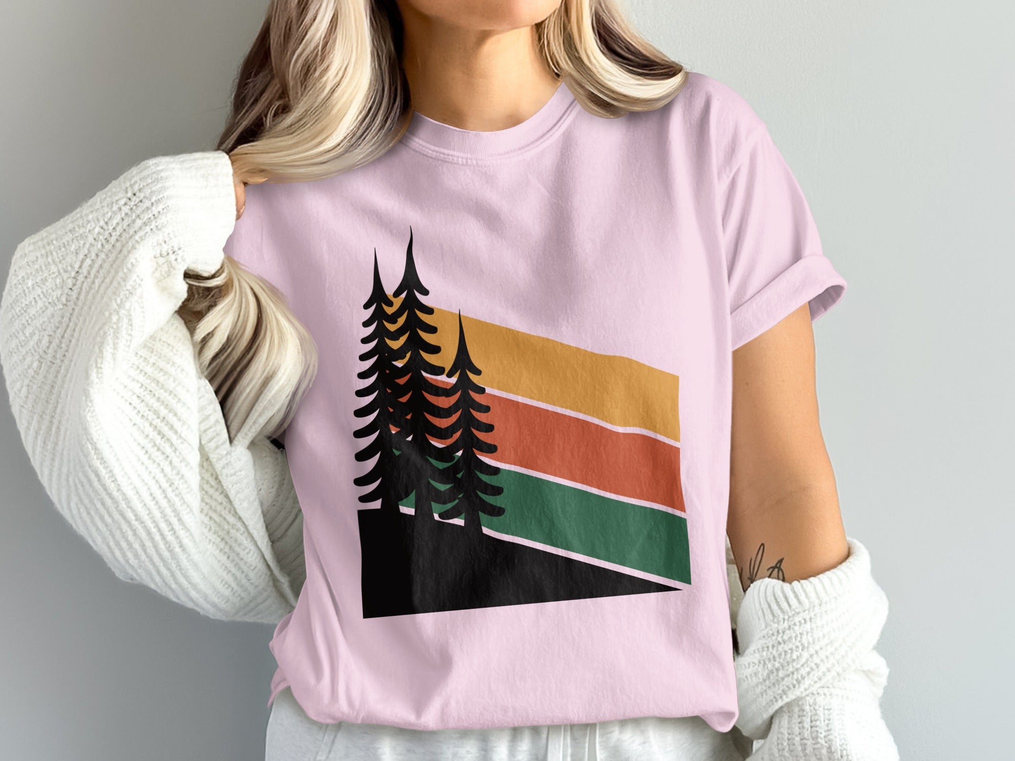 Pink t-shirt with abstract forest and mountain sunset graphic.
