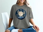 Grey t-shirt with a circular scene of moon, mountains, and trees.