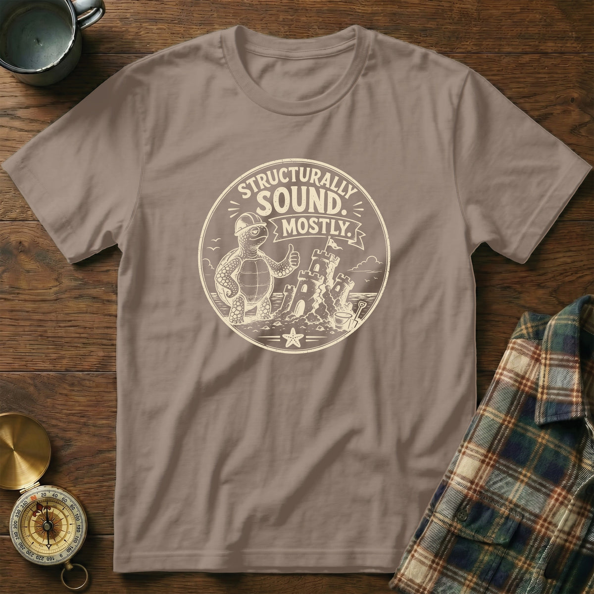 T-shirt with a cartoon turtle wearing a hard hat and giving a thumbs up, next to a sandcastle.