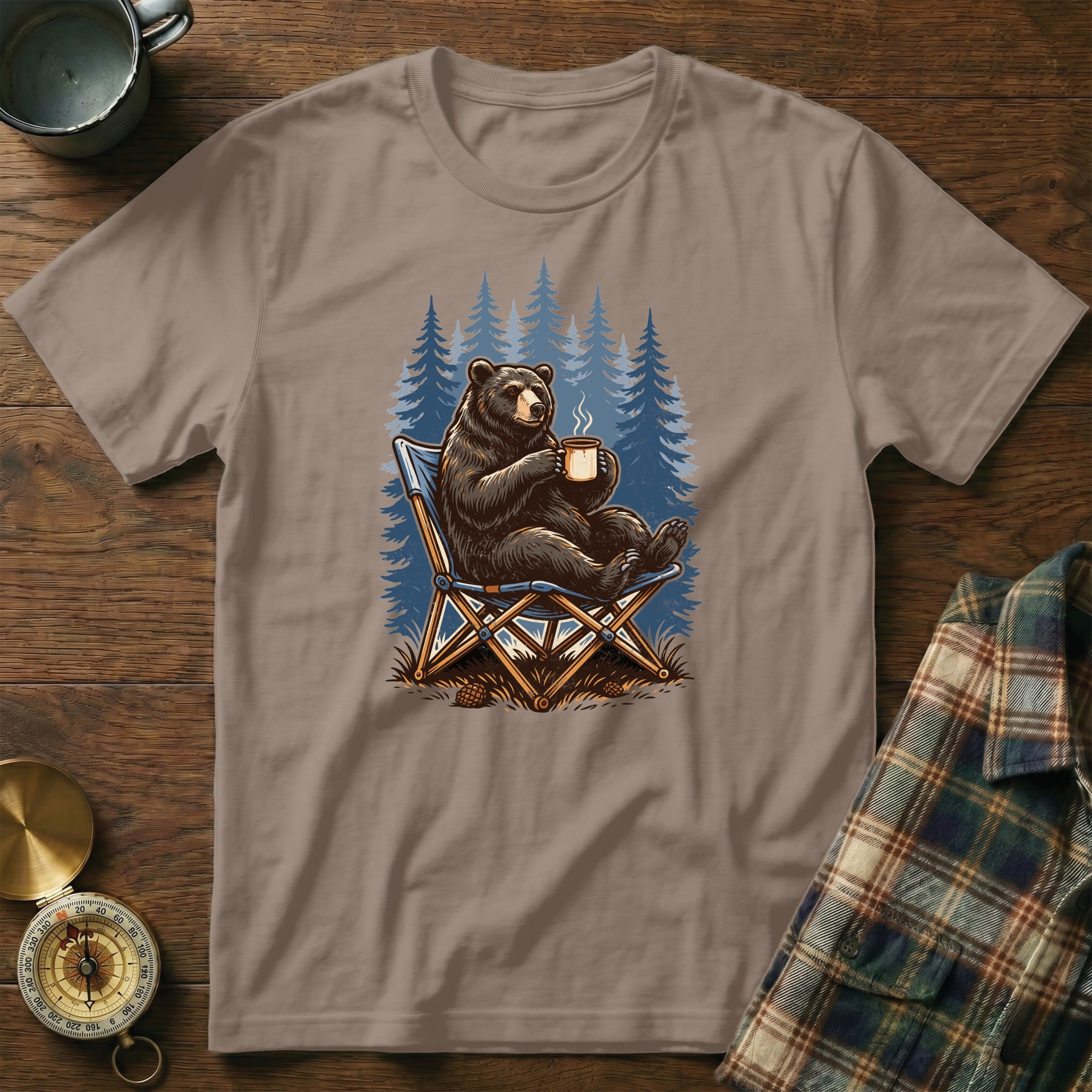 Bear relaxing in a chair with coffee, forest background graphic on t-shirt.