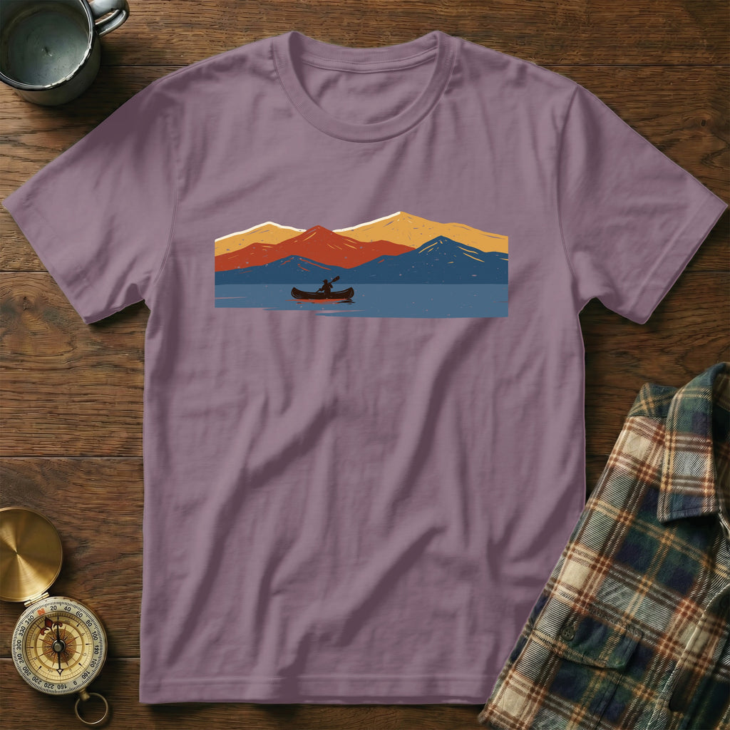 Purple t-shirt with a graphic of a canoe on a lake with colorful mountains.