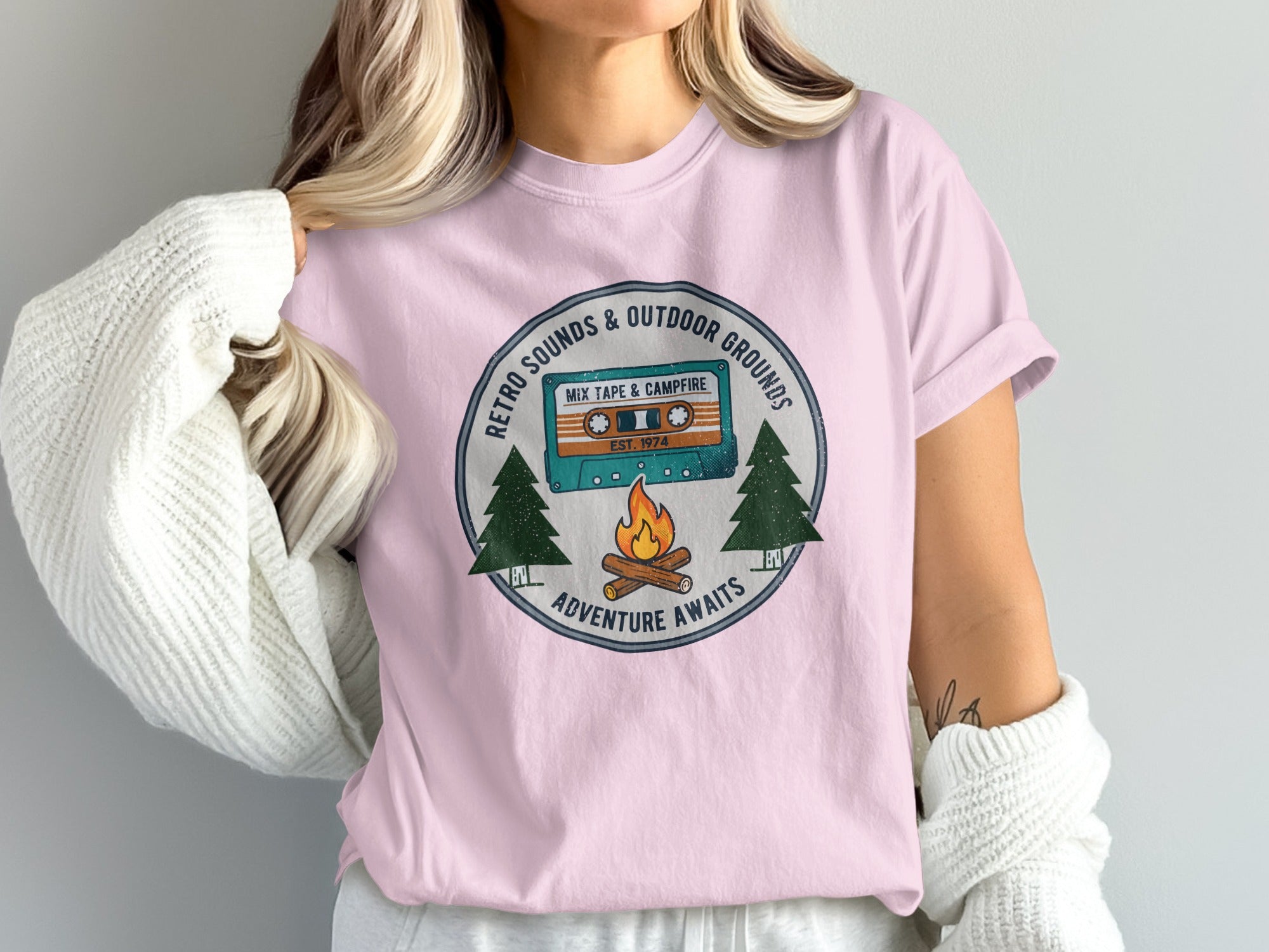 Pink t-shirt with vintage cassette tape, campfire, and trees graphic.