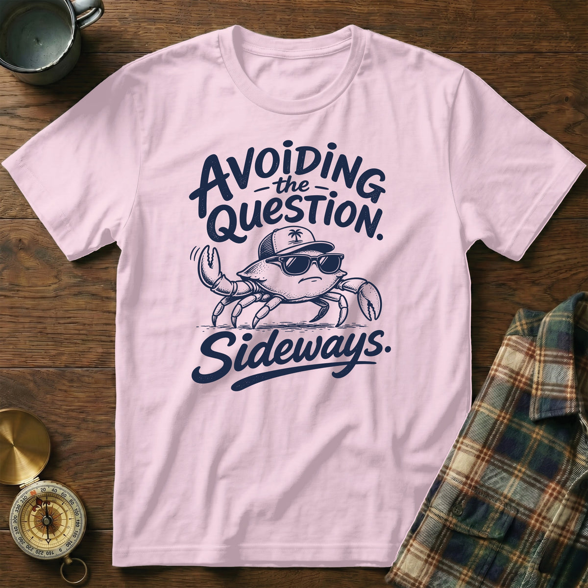 A pink t-shirt featuring a graphic of a crab wearing sunglasses and a cap, with the text avoiding the question sideways.
