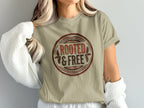 Tan t-shirt with a circular graphic reading "ROOTED & FREE" with leafy accents.