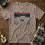 T-shirt with a graphic of a rowboat on a lake at sunset with mountains.