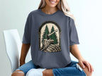 T-shirt graphic with axe, tree stump, and woodpile framed by an arch.