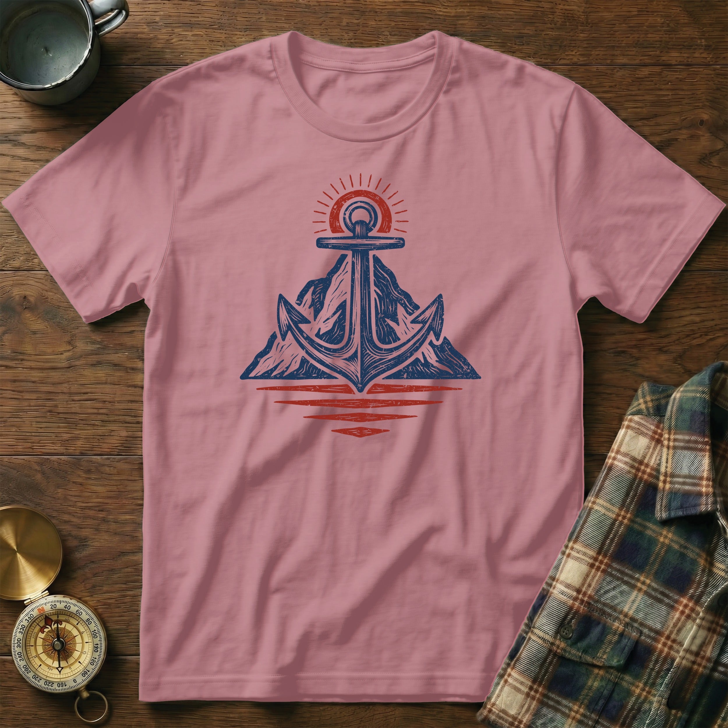 Pink t-shirt with a blue anchor over mountains and red sun graphic.