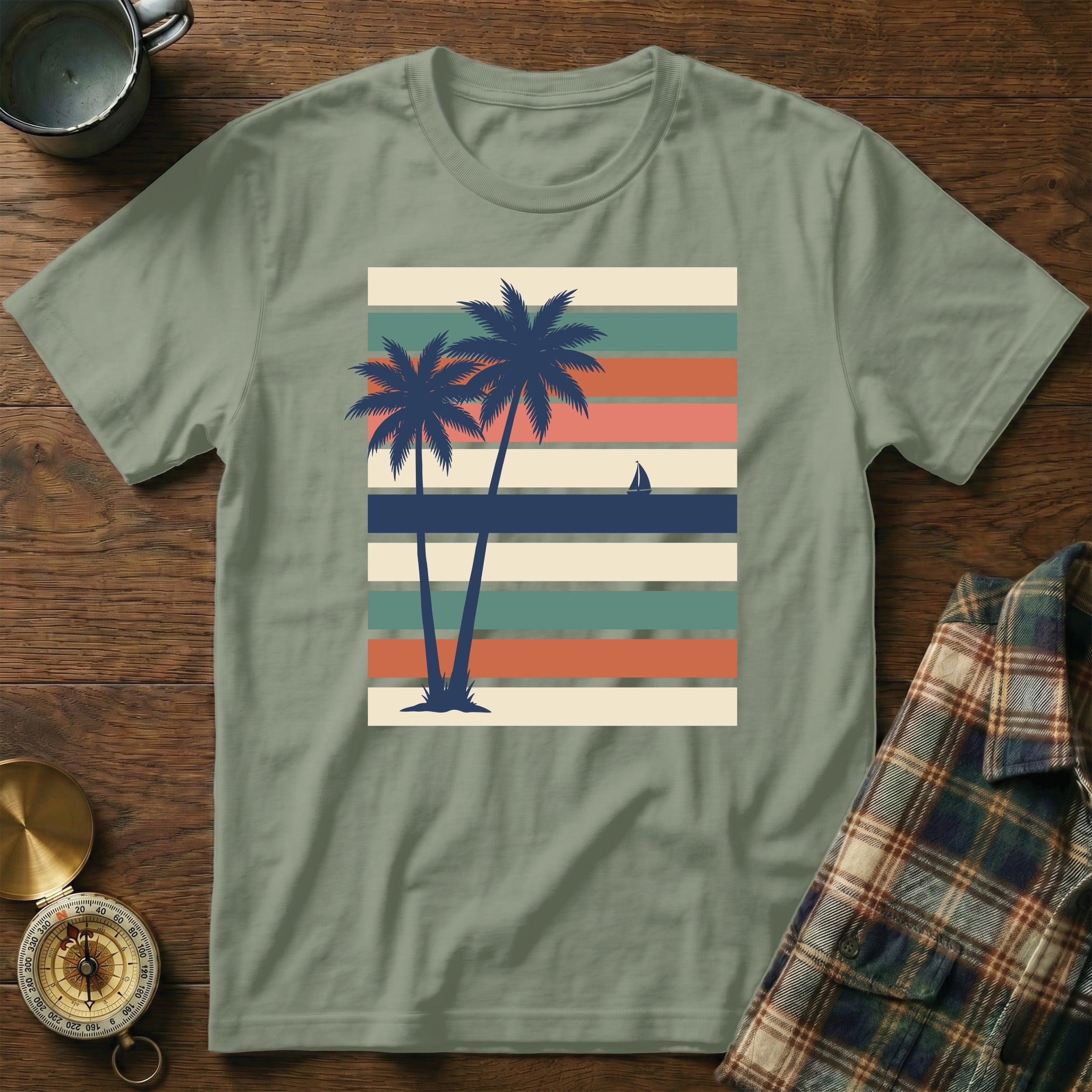 Olive green t-shirt with retro palm trees and sailboat on striped background.