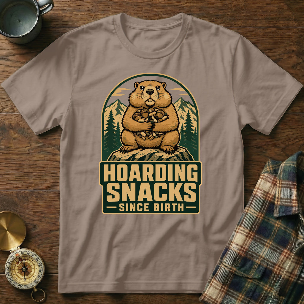 Groundhog with nuts hoard in mountain graphic, "Hoarding Snacks Since Birth" text.