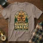 Groundhog with nuts hoard in mountain graphic, "Hoarding Snacks Since Birth" text.