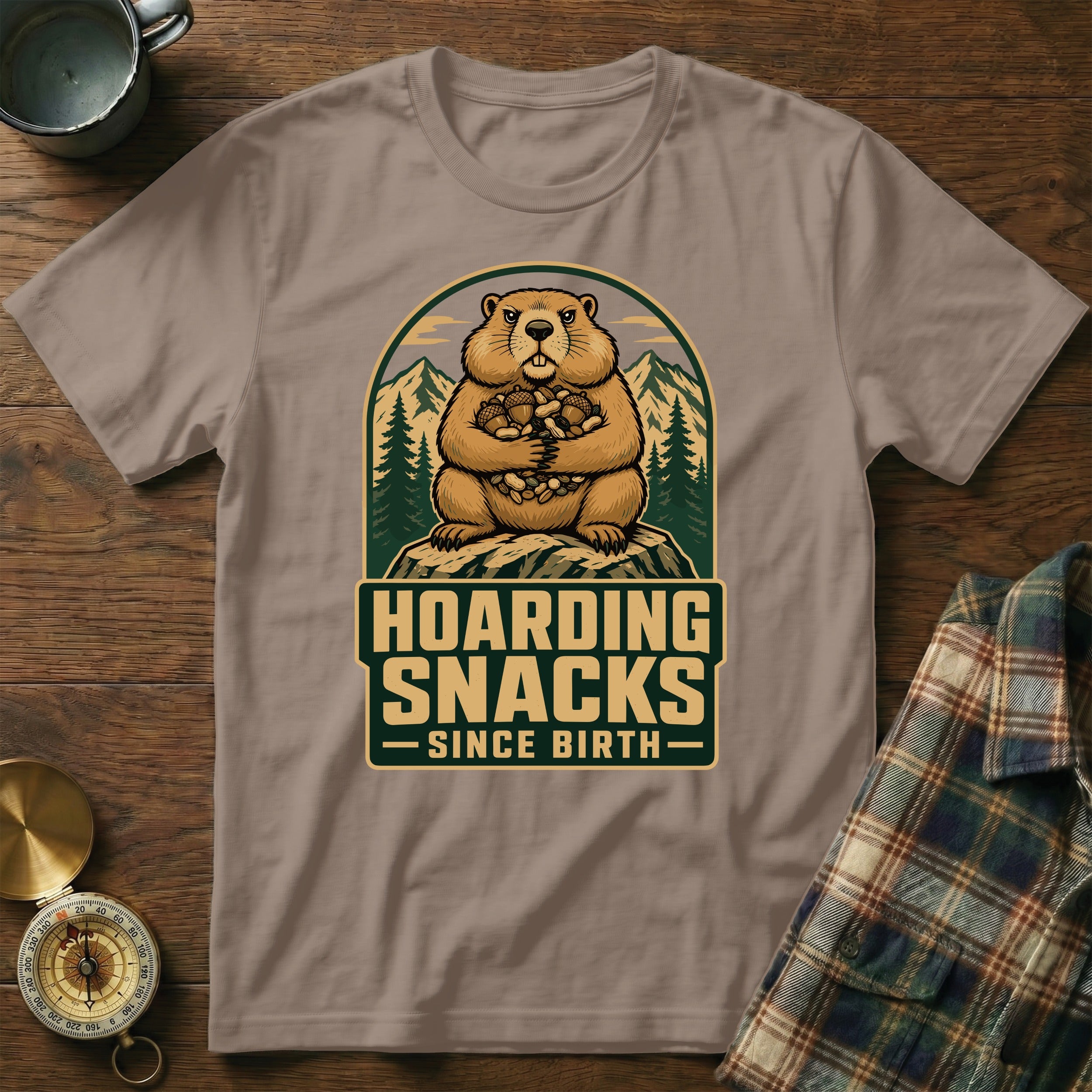 Groundhog with nuts hoard in mountain graphic, "Hoarding Snacks Since Birth" text.