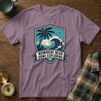 T-shirt with crest design featuring palm tree, wave, and text "Nowhere Near Done Exploring".