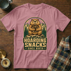 Groundhog hoarding snacks design on a pink t-shirt with text "HOARDING SNACKS SINCE BIRTH".