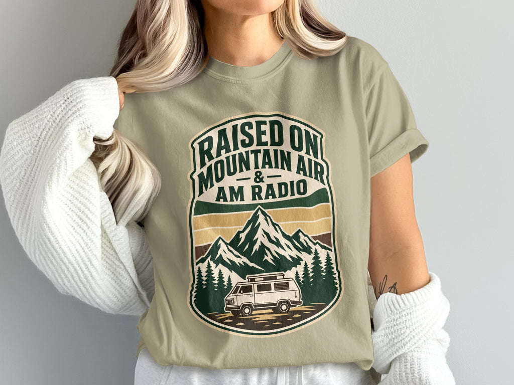 T-shirt with "Raised on Mountain Air & AM Radio" text and mountain, trees, van graphic.