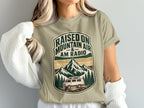 T-shirt with "Raised on Mountain Air & AM Radio" text and mountain, trees, van graphic.