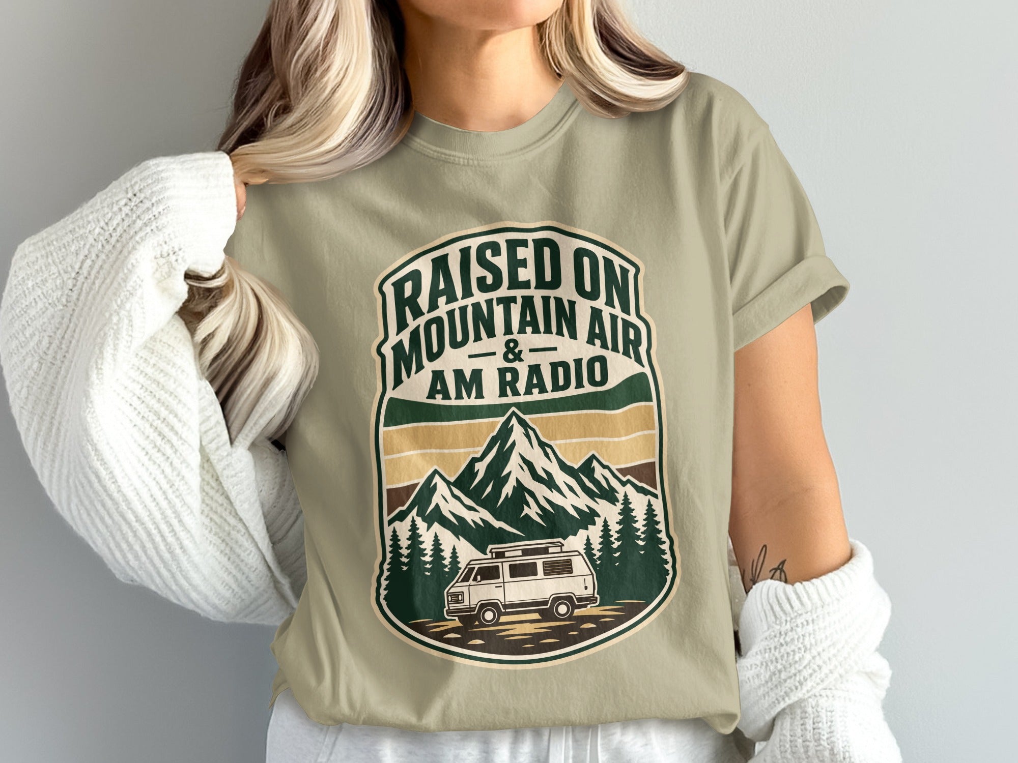T-shirt with "Raised on Mountain Air & AM Radio" text and mountain, trees, van graphic.