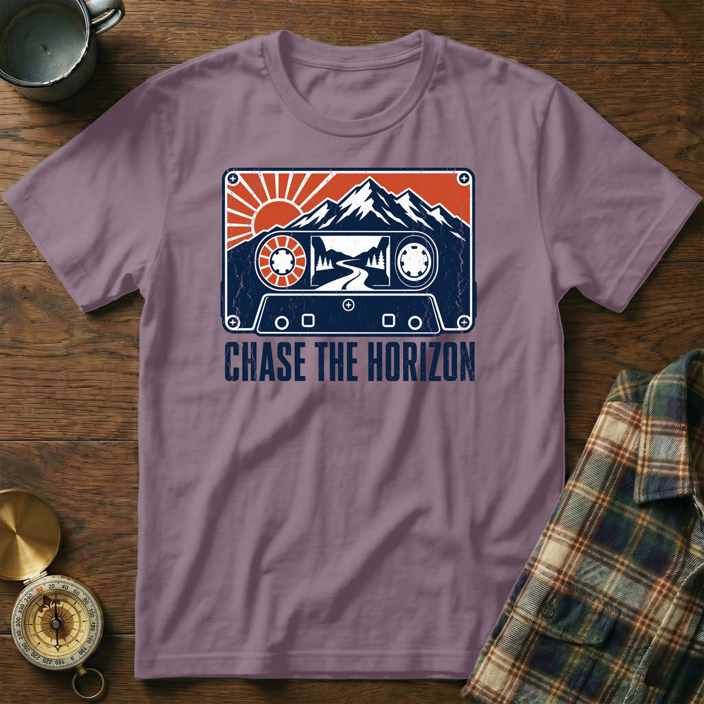 T-shirt with cassette tape design featuring mountains, sun, and road. Text: Chase the Horizon.