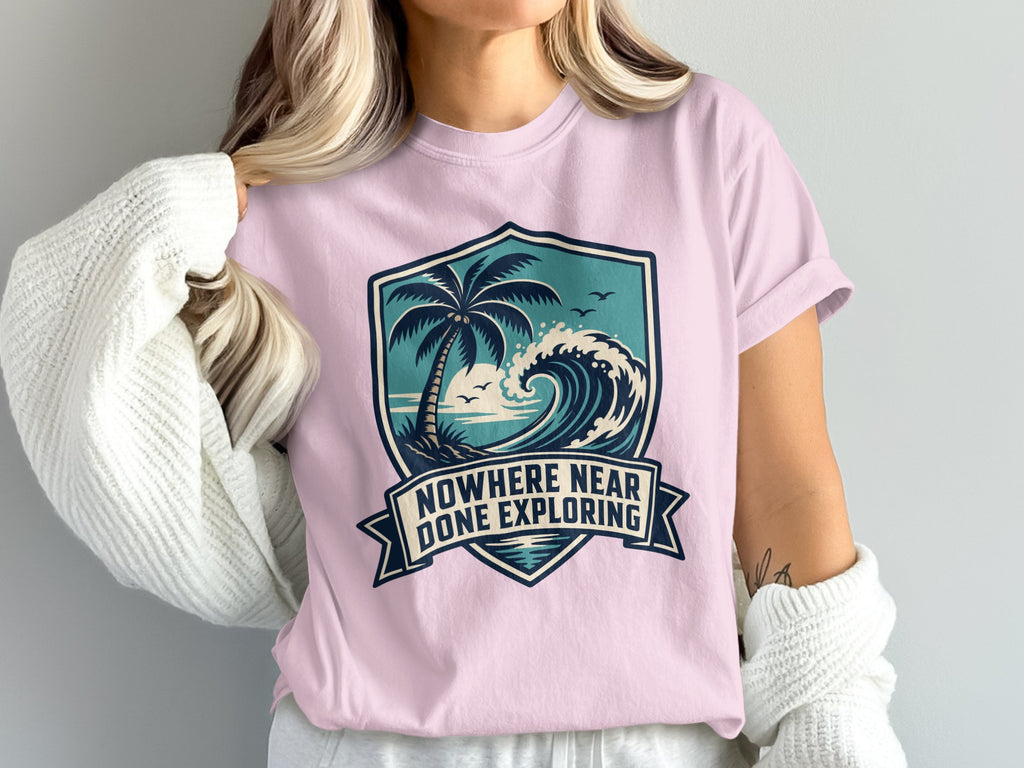 Pink t-shirt featuring a shield graphic with a palm tree, wave, and text.