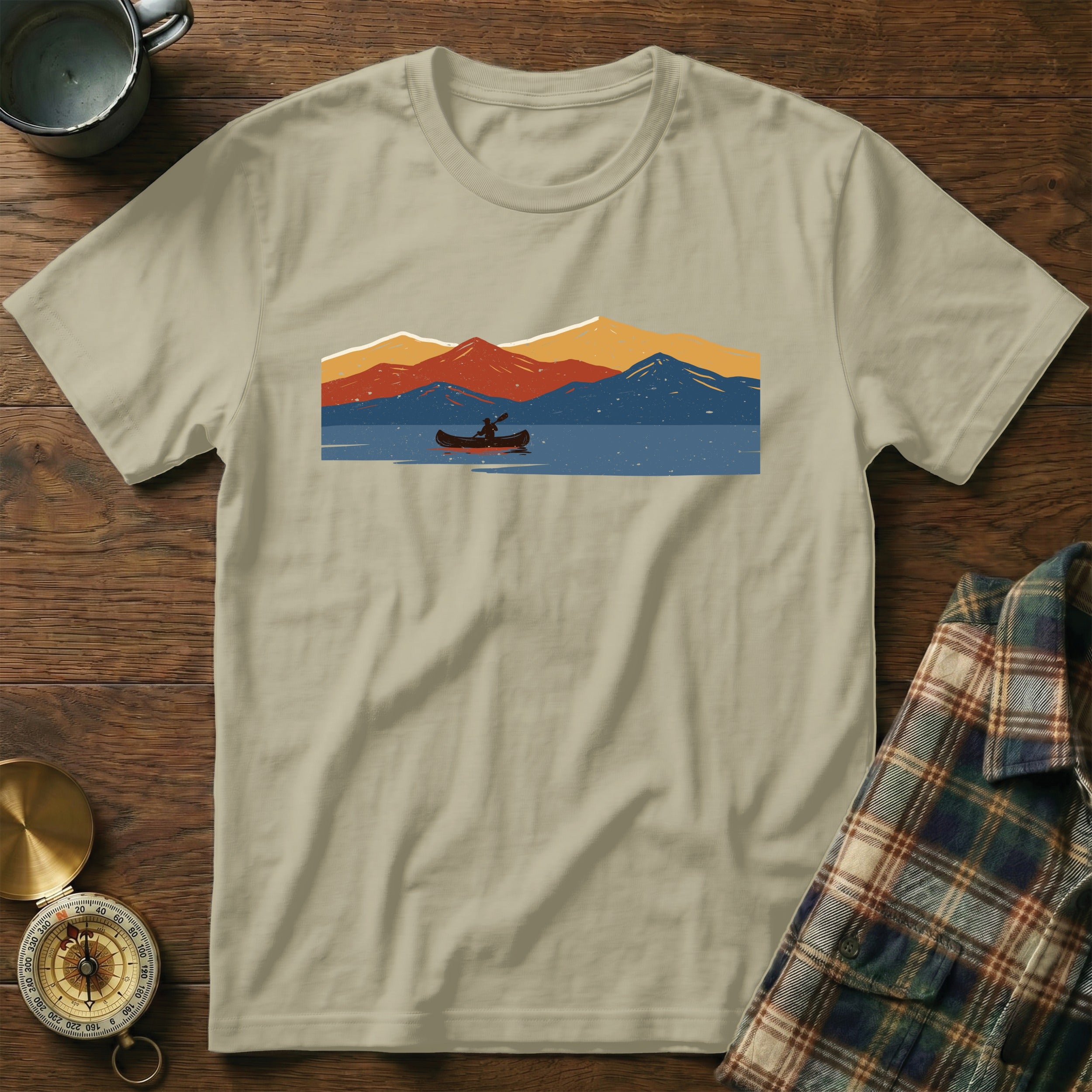 T-shirt with a vintage design of a person canoeing on a lake with mountains.