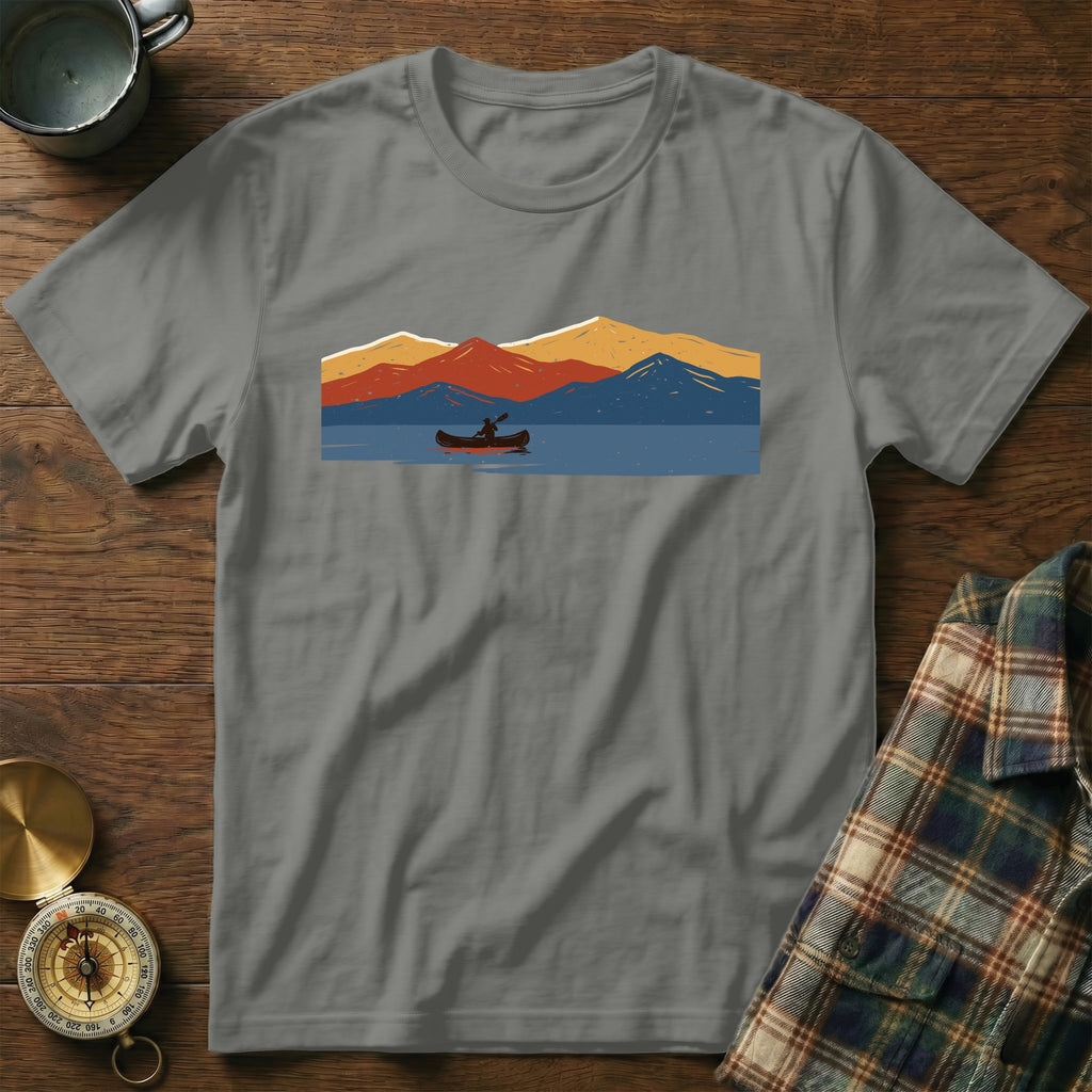 Gray t-shirt with a graphic of a person canoeing on a lake with colorful mountains.