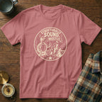 Pink t-shirt with a graphic of a turtle giving a thumbs up next to a sandcastle.
