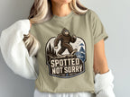 Bigfoot wearing sunglasses walking on a cliff, with text "Spotted Not Sorry".