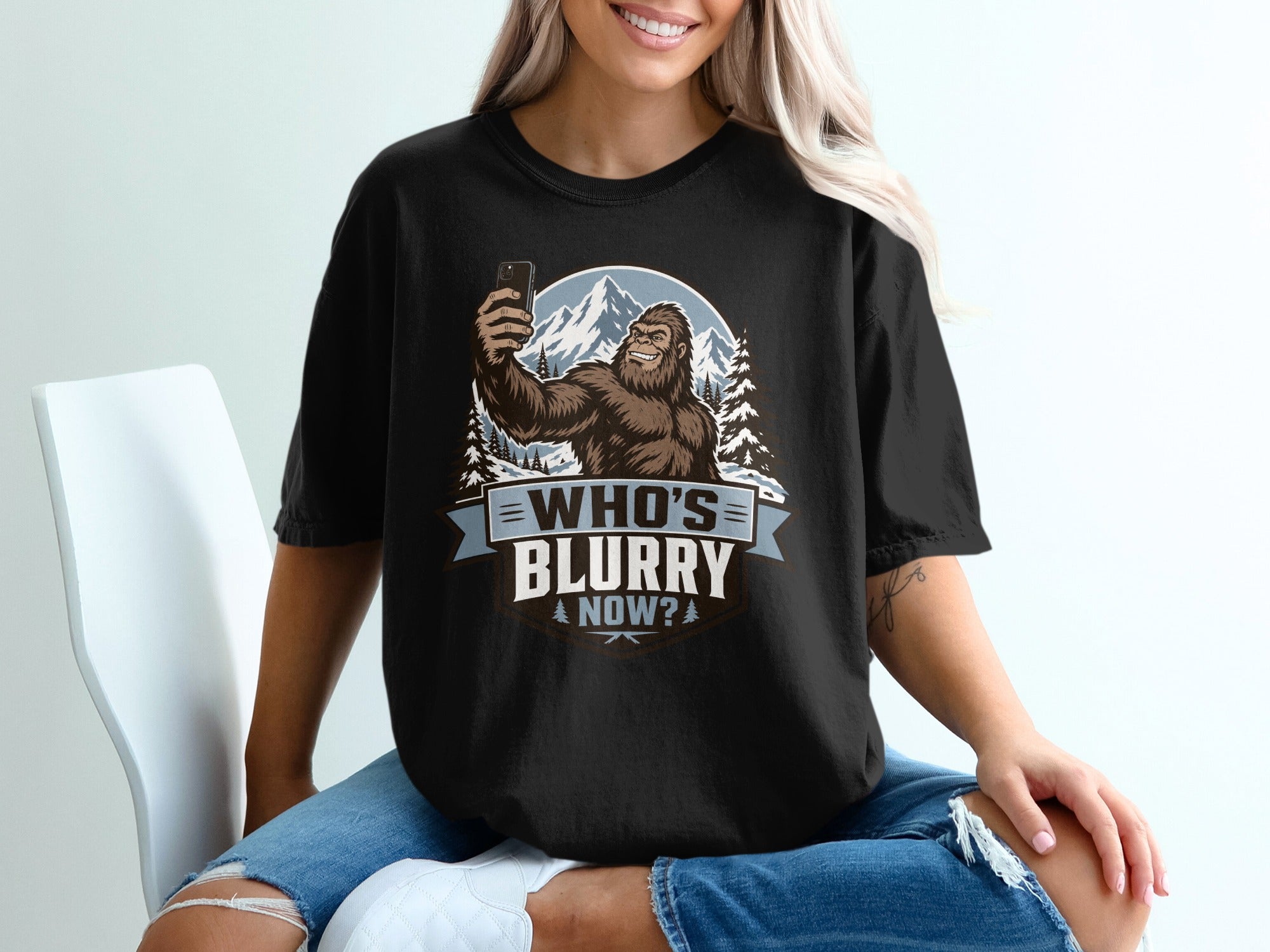 Bigfoot taking a selfie in a snowy mountain landscape with text "Who's Blurry Now?"