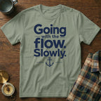 Sage green crewneck t-shirt with navy blue text reading Going with the flow. Slowly. and an anchor graphic.