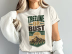 White t-shirt with "TREELINE OR BUST" text and mountain, sun, and tree graphic.