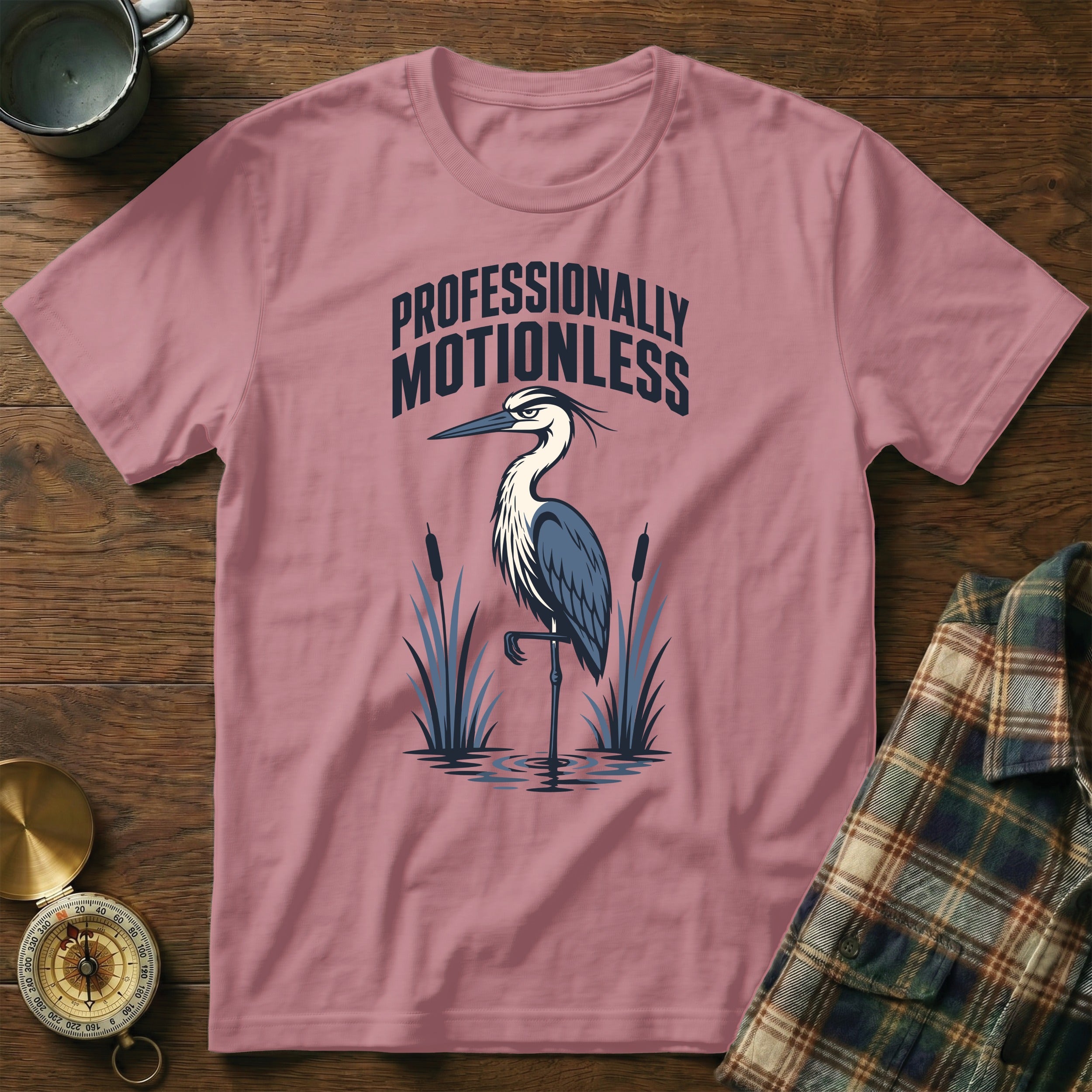Pink t-shirt with a heron and cattails graphic. "Professionally Motionless" text above.