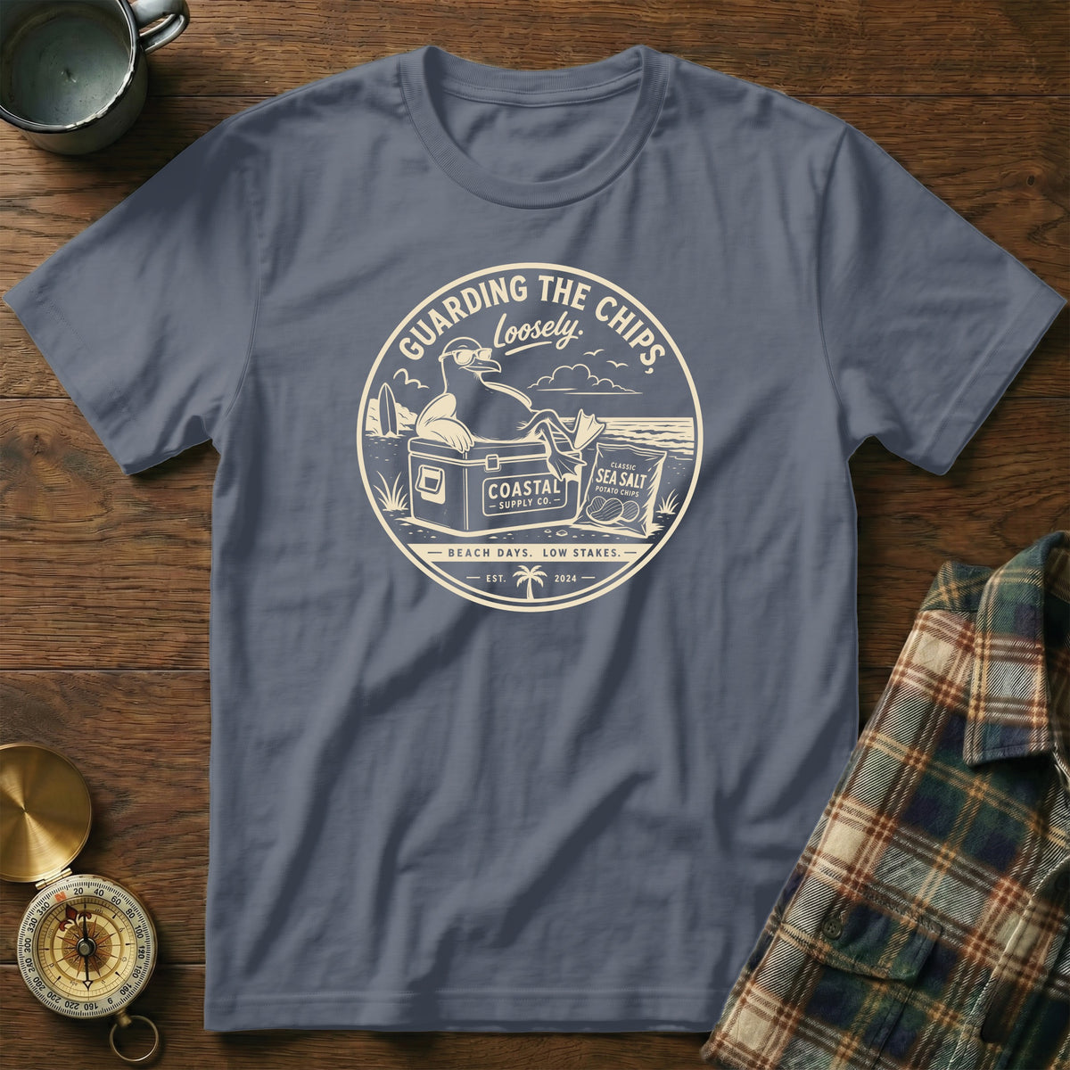Shirt with beach scene graphic: seagull, cooler, chips, waves, text "Guarding the Chips Loosely."