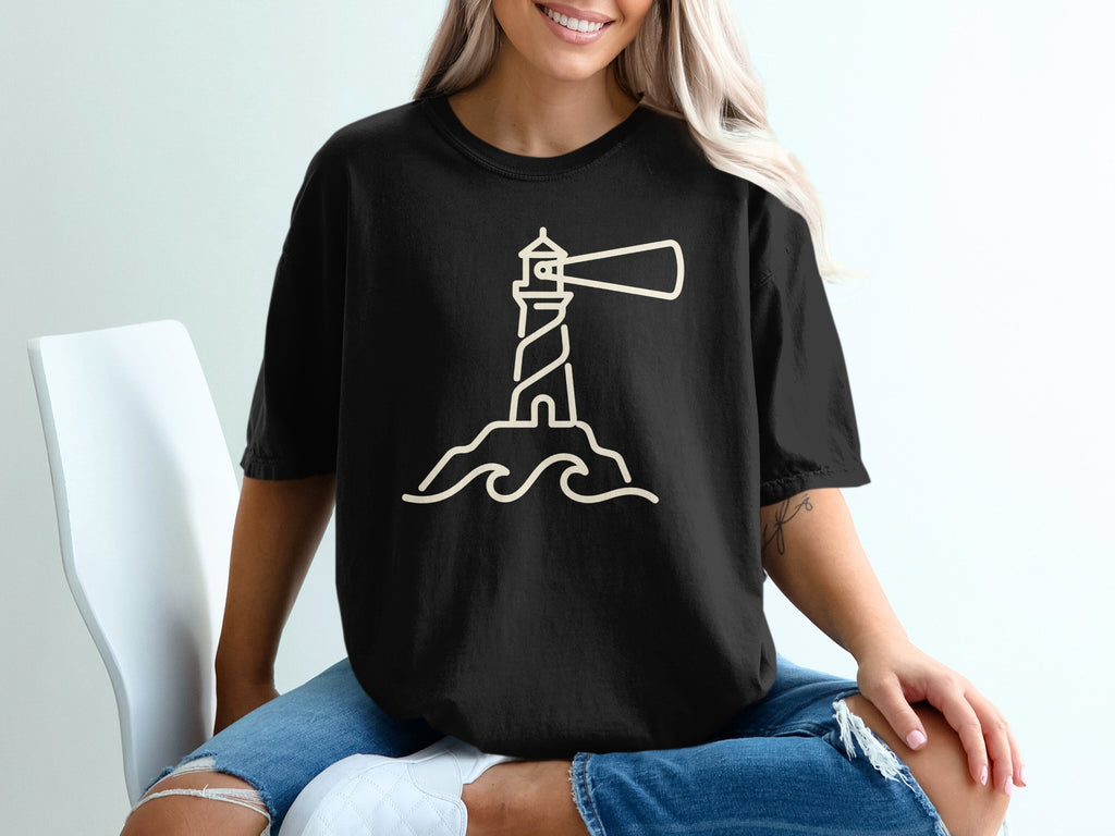 Black t-shirt with a beige outline graphic of a lighthouse on waves.