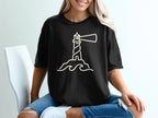 Black t-shirt with a beige outline graphic of a lighthouse on waves.