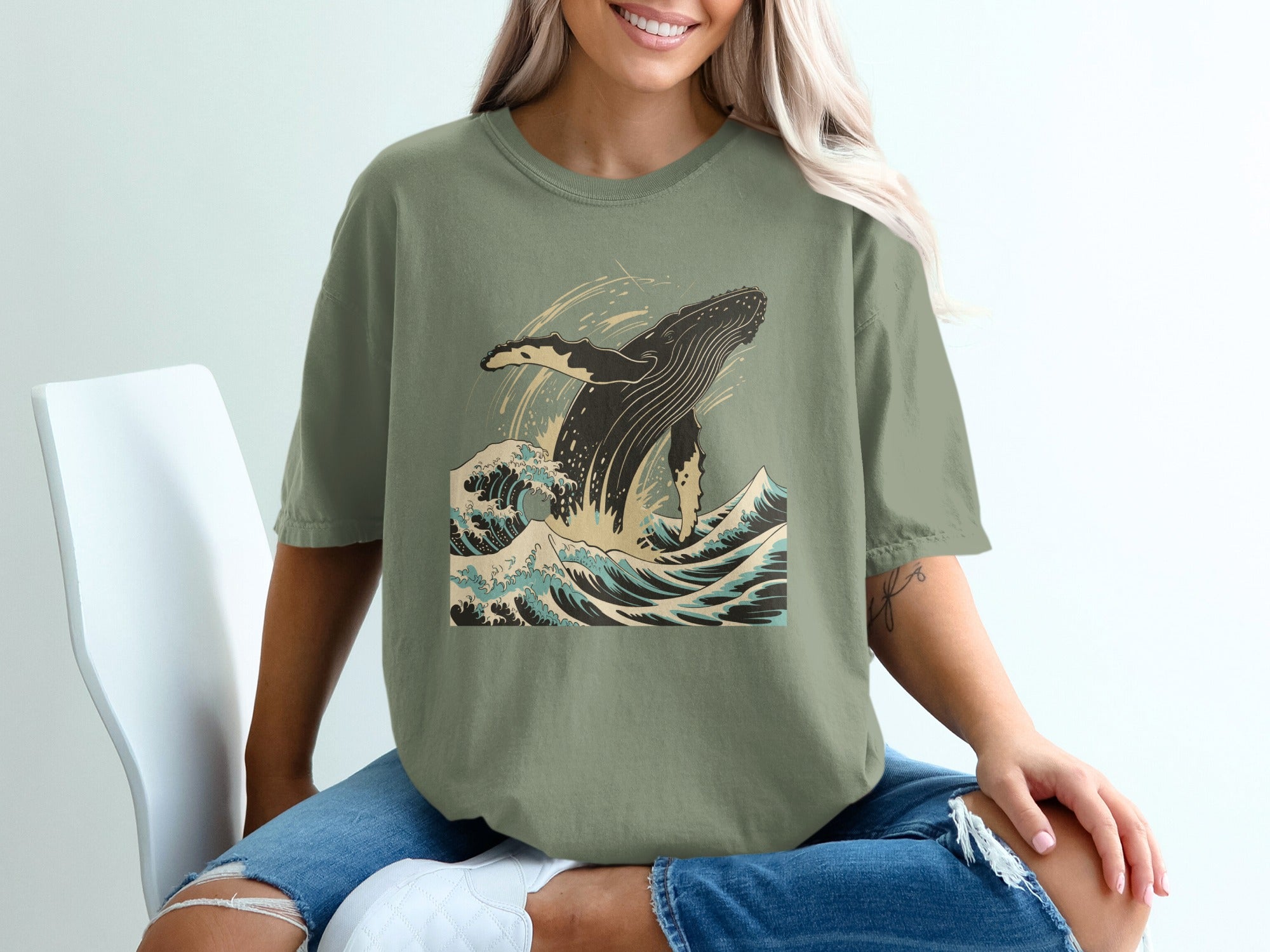 Green t-shirt with a breaching whale and stylized waves graphic.