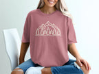 Pink t-shirt with a minimalist outline of mountains and pine trees on the front.