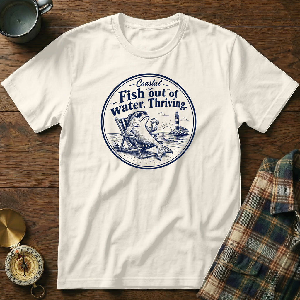 Off-white crewneck t-shirt featuring a blue graphic of a fish relaxing in a beach chair with a drink.