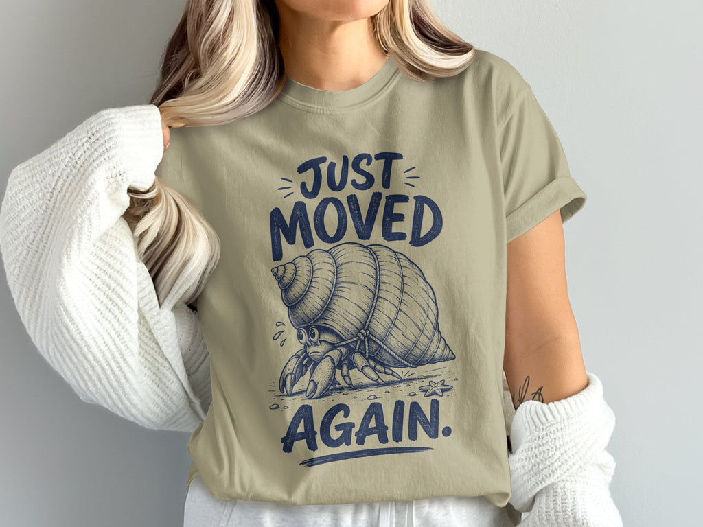 Hermit crab graphic on tan t-shirt with text "JUST MOVED AGAIN."