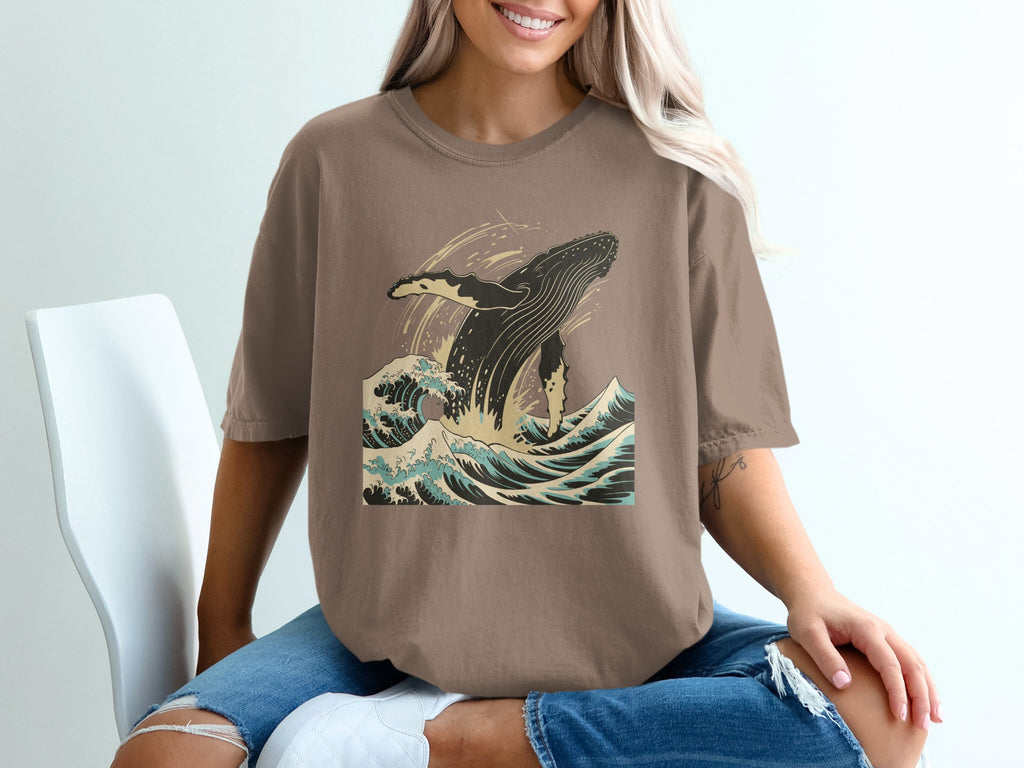 Brown t-shirt with graphic of a humpback whale breaching in ocean waves.