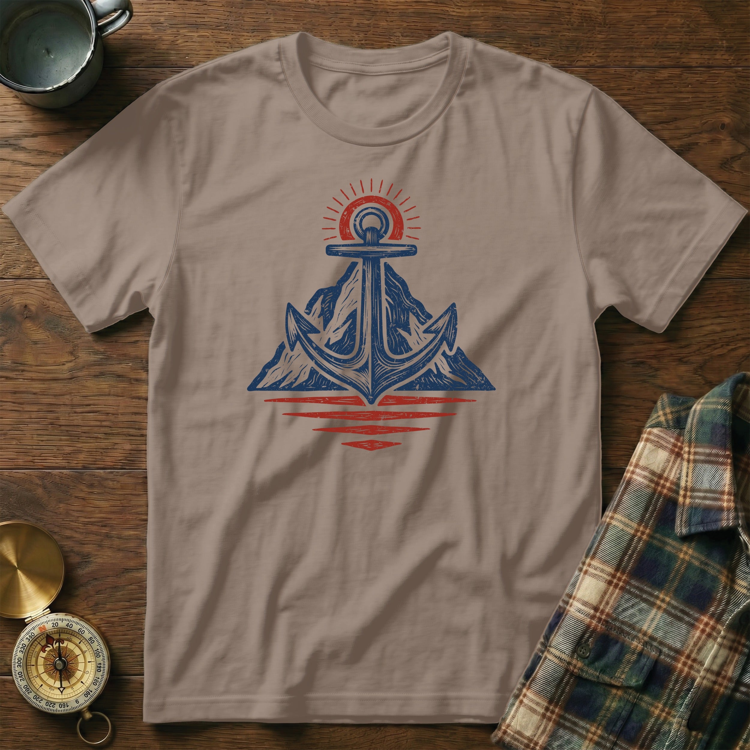 Brown t-shirt with a blue anchor on mountains graphic and red sun.