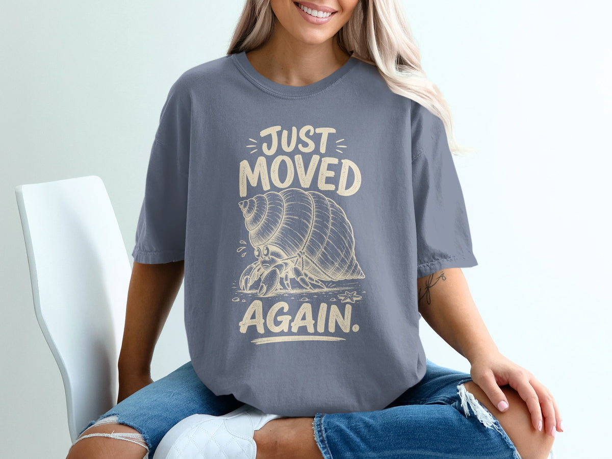 Grey t-shirt with a graphic of a hermit crab and text that reads "JUST MOVED AGAIN."
