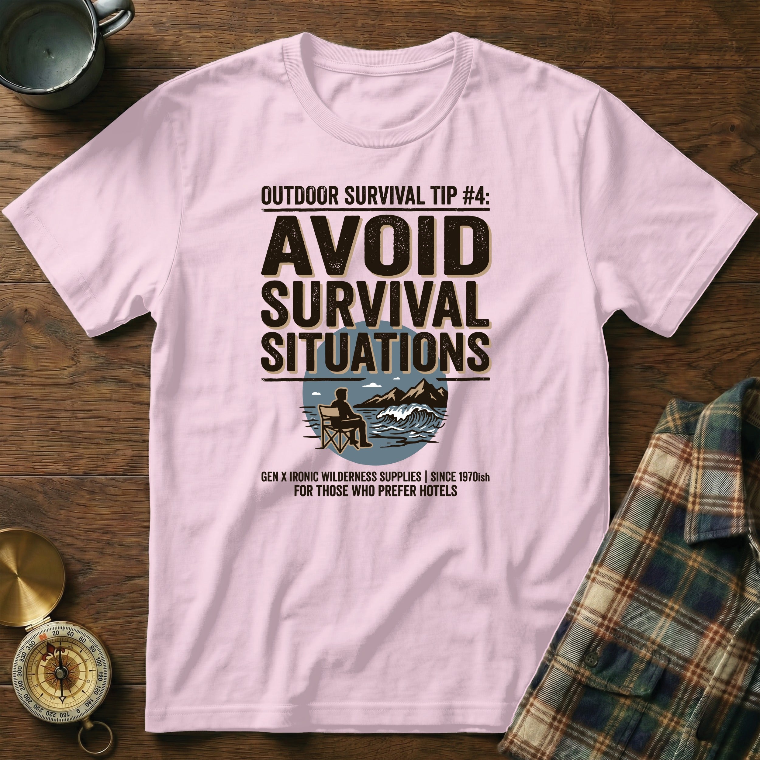 Pink t-shirt with "AVOID SURVIVAL SITUATIONS" graphic and ironic wilderness text.