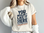 White t-shirt with blue and red text reading "You wouldn't like it here. That's why we do cold water. Wind. No complaints."