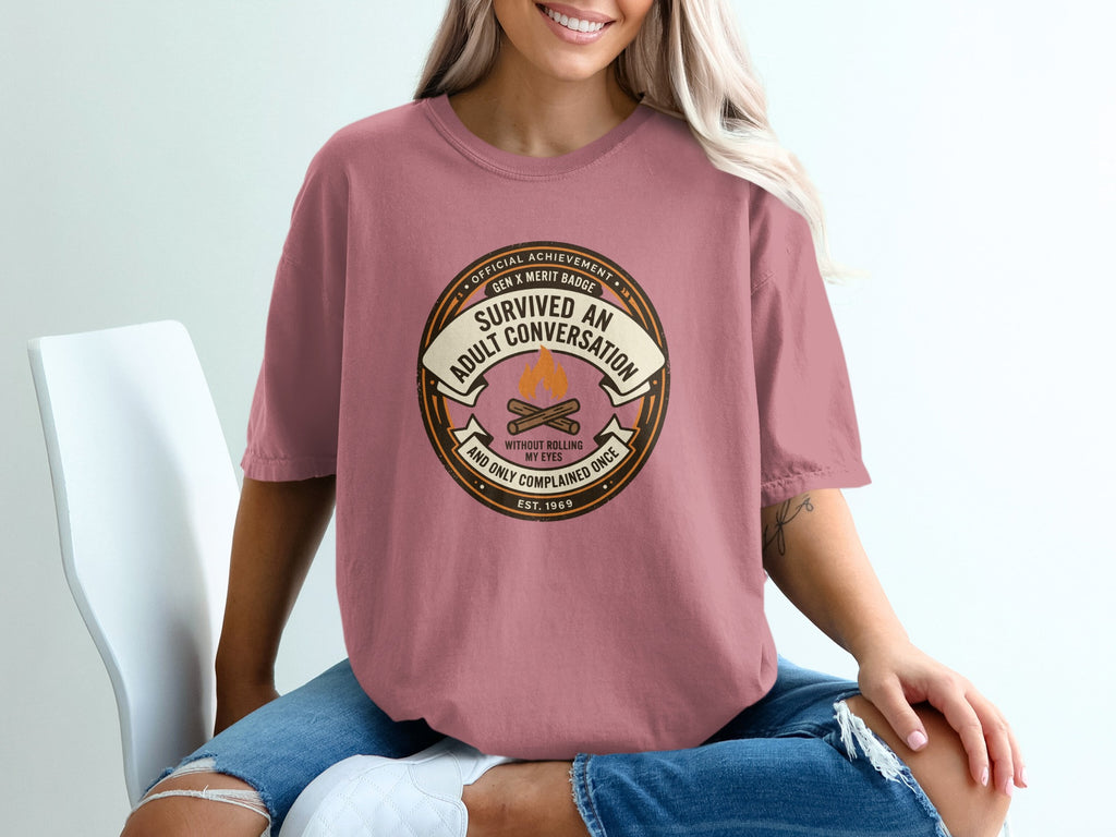 T-shirt with "Survived an adult conversation" merit badge design.