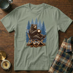 Bear in camping chair with coffee mug in front of pine trees illustration.