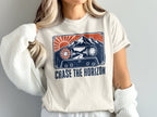 T-shirt graphic of a cassette tape with mountains, sun, and text "CHASE THE HORIZON".