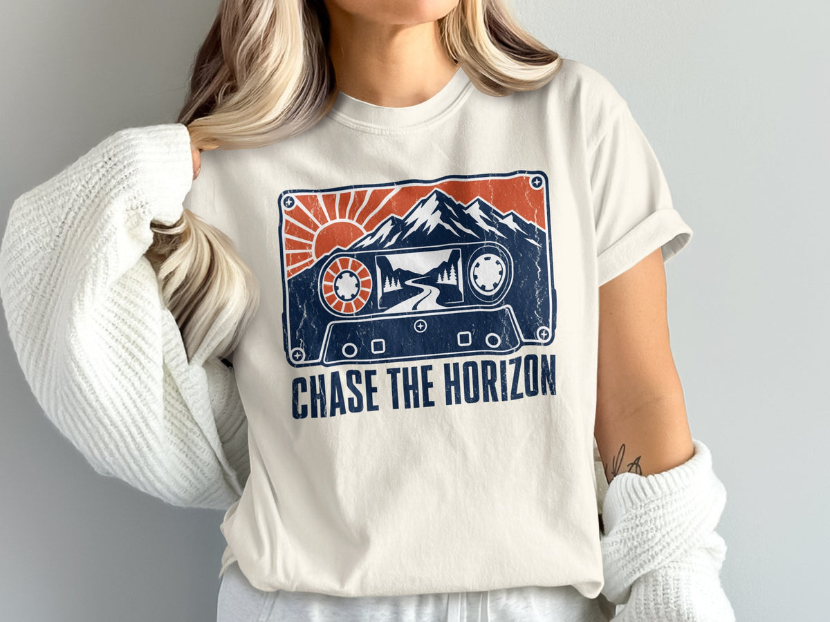 T-shirt graphic of a cassette tape with mountains, sun, and text "CHASE THE HORIZON".