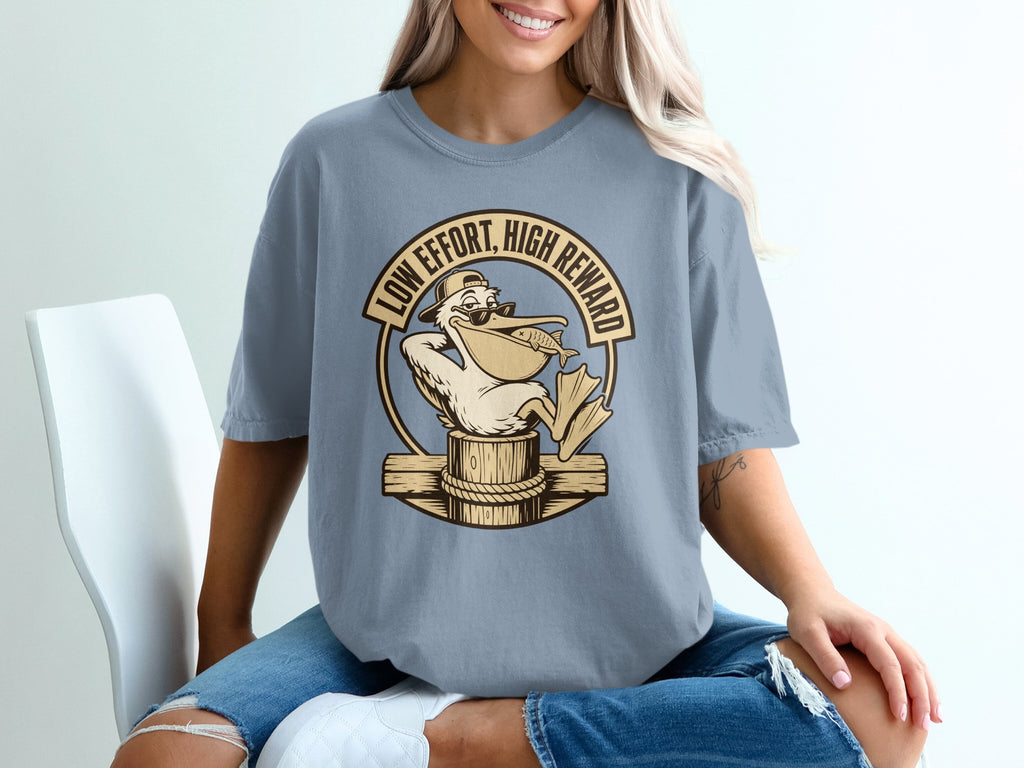 T-shirt with graphic of pelican wearing sunglasses holding fish, text "Low Effort, High Reward".
