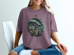 Woman wearing purple t-shirt with circular graphic of oar and ocean waves.